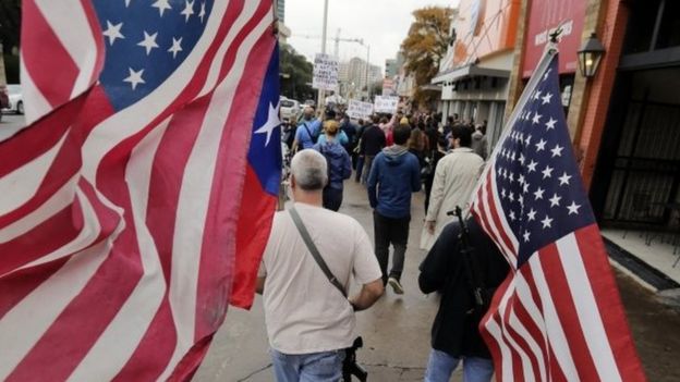 Gun rights activists Phil Newsome, left, and Jason Mosley, right, carry guns and flags as they march near the University of Texas, on 12 December 2015, in Austin, Texas.