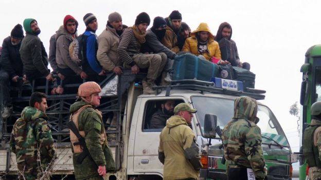 Syrian government forces and Russian soldiers keep watch as civilians and fighters are evacuated from a rebel-held area of Aleppo towards rebel-held territory in the west of Aleppo's province on 16 December 2016