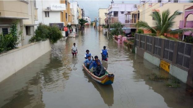 Indian people make their way in a canoe on a flooded street following heavy rain in Chennai on November 16, 2015.