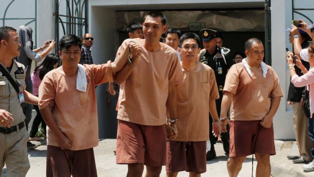 Four activists in handcuffs and prison uniforms, detained after posting critical comments on Facebook, leave a military court in Bangkok on 10 May 2016