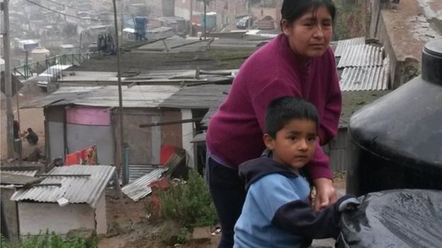 Lydia Sevillano and her son Andy (3) stand by their water tanks