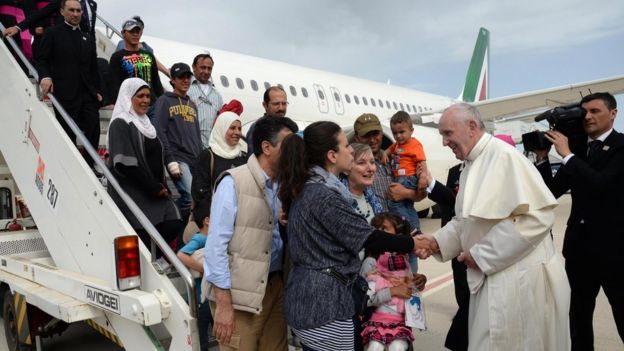Pope Francis greets migrants stepping off a plane in Italy