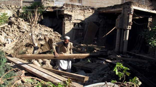 A man clears wooden beams from the rubble of a house after it was damaged by an earthquake in Mingora, Swat, Pakistan October 27, 2015.