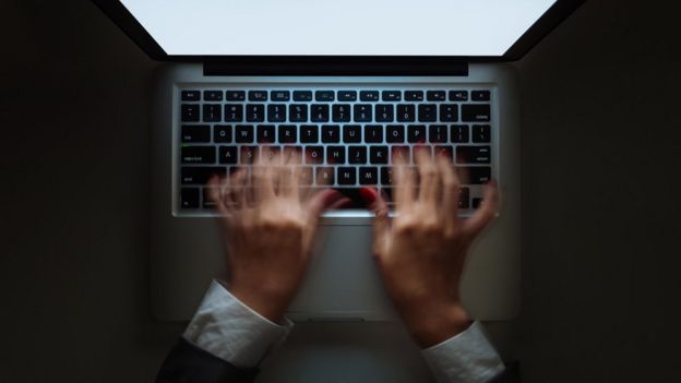 Manos tecleando rápido sobre una laptop.