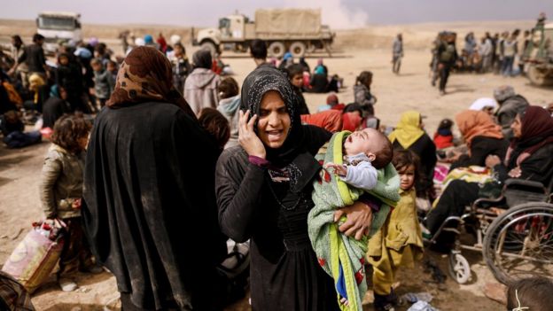 A displaced Iraqi woman talks on the phone as Iraqi forces battle with Islamic State militants in western Mosul, Iraq (27 February 2017)