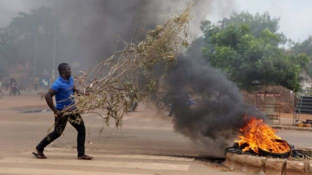 Protester throws tree branches on a burning tyres in Ouagadougou, Burkina Faso, 18 September 2015