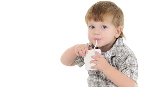 A toddler drinking from a juice carton