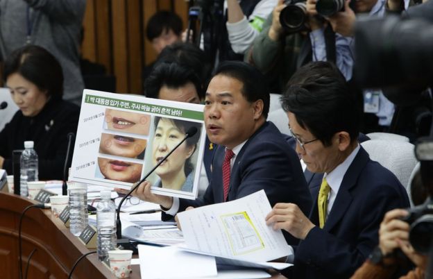 Opposition People's Party lawmaker Lee Yong-Joo shows impeached President Park Geun-Hye's three pictures combo taken on May during a parliamentary hearing over the Choi Soon-sil gate probe at the National Assembly on December 14, 2016 in Seoul, South Korea.