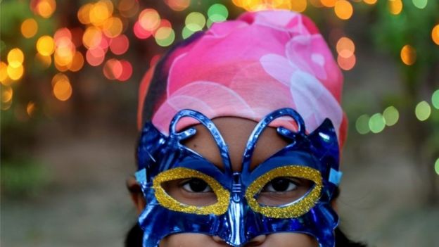 An Indian girl wears a mask as she poses for a photograph at a public square during a Christmas celebration in Calcutta, eastern India, 21 December 2015.