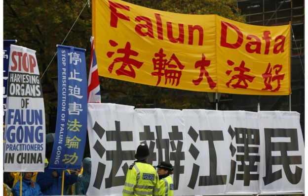 Two police officers stand guard in front of supporters of the Falun Gong as they protest outside Downing Street as they wait for the arrival of Chinese President Xi Jinping in London, Wednesday, 21 October 2015