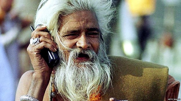 A sadhu uses a mobile phone during Maha Kumbh Mela at Prayag in Allahabad