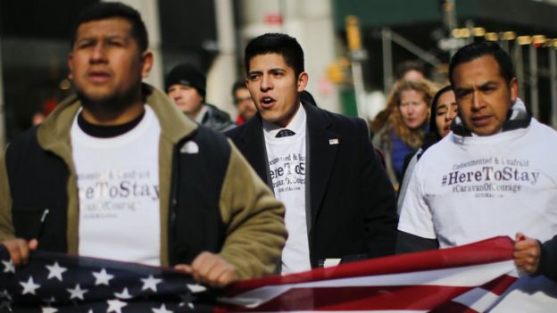 Jóvenes latinos marchan con una bandera de Estados Unidos en sus manos.