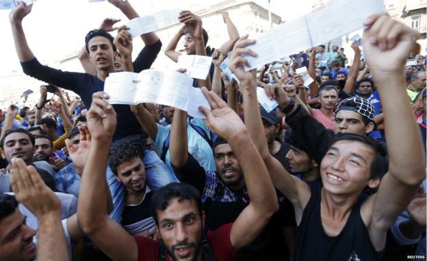 Migrants wave their train tickets outside the main Eastern Railway station in Budapest, Hungary, 1 September 2015