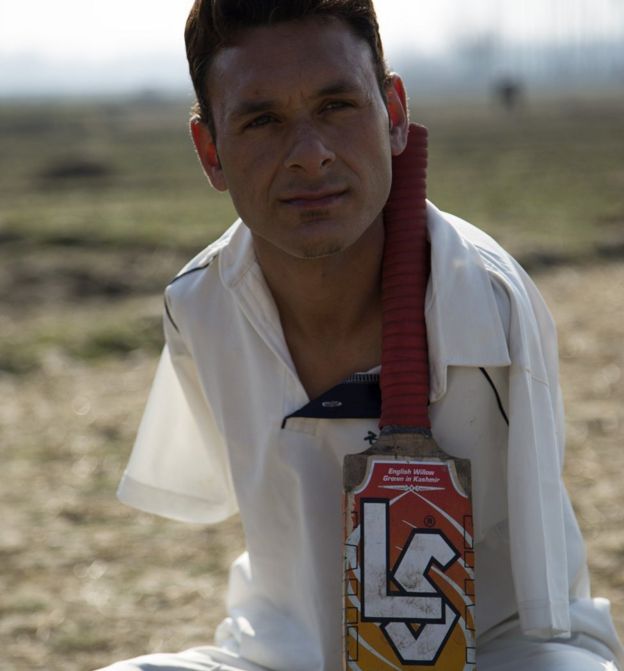 Amir holds the cricket bat between his neck and shoulder