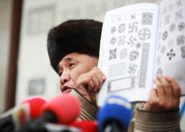 Sevjidiin Sukhbaatar, the father of injured Mongolian rapper Amarmandakh Sukhbaatar, displays a book showing traditional swastika patterns at a press conference about his son in Ulan Bator, Mongolia, on December 2, 2016.