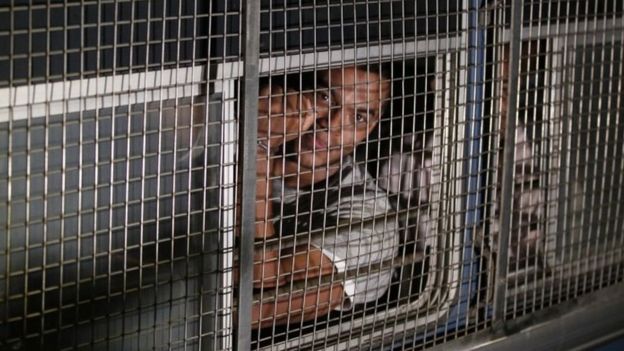 Yoshitha Rajapaksa shows hand cuffs to the media as he is taken away in a prison bus. Photo: 30 January 2016
