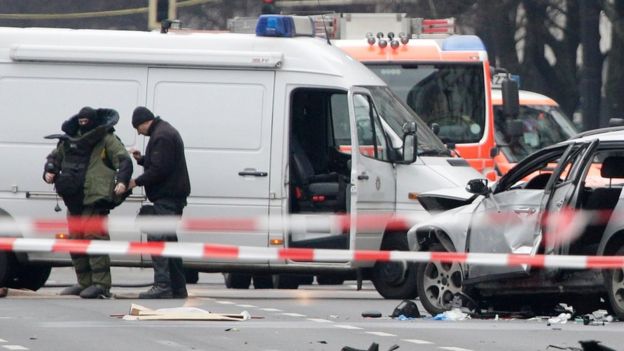 A bomb disposal specialist puts on protective gear beside an exploded car as he investigates the site of the blast in Berlin, Germany, Tuesday, March 15, 2016.
