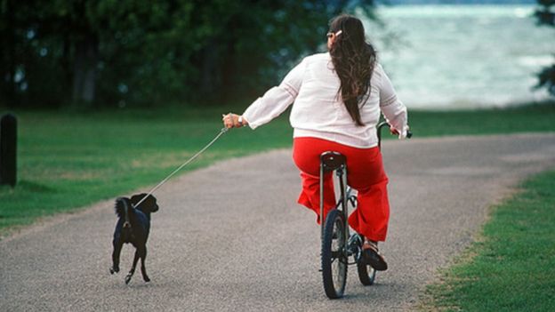 Una mujer en una bicicleta acompañada de un perro