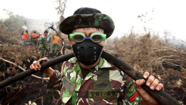 A fire fighter, wearing a mask and swimming goggles to protect himself from the smoke