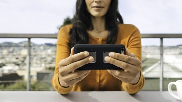 Woman holding smartphone with Kardia Mobile sensor stuck on the back