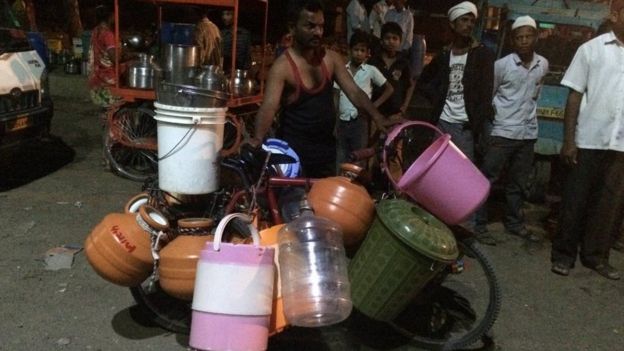 A man waits with water containers to be filled in Maharashtra