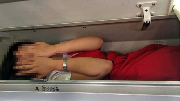 This photo seen on the WeChat account of the 'Civil Aviation Tabloid' channel, shows an air stewardess lying in an overhead luggage compartment