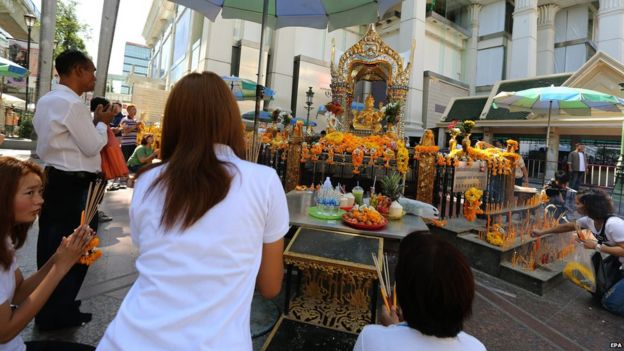 Tourists offer prayers to a statue of the Hindu god of creation Lord Brahma at the Erawan Shrine
