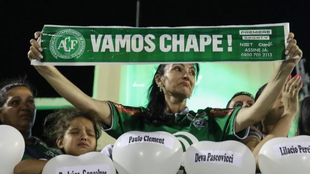 Mujer con un cartel que dice Vamos Chape durante la vigilia en el estadio del club