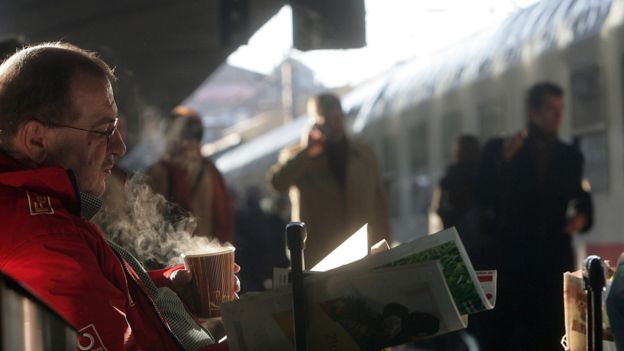 Commuter drinking coffee on railway platform in Hamburg