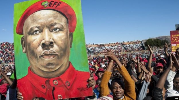 Supporters of the Economic Freedom Fighters (EFF), South Africa's third-biggest party, hold a placard with the portrait of EFF leader Julius Malema as part of the celebration of the party's second anniversary on 25 July 2015, at the Olympia Park Stadium in Rustenburg