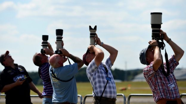 Aircraft enthusiasts photograph an air display at the Farnborough air show