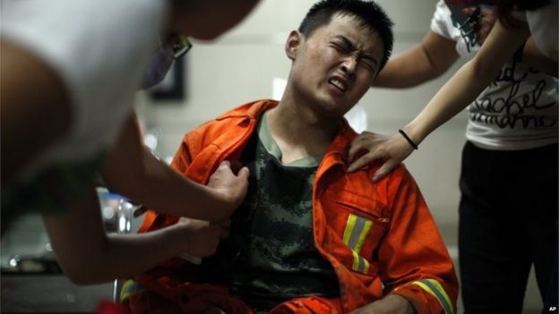 An injured firefighter grimaces as he is examined in a hospital following explosions in Tianjin municipality, Aug. 13, 2015