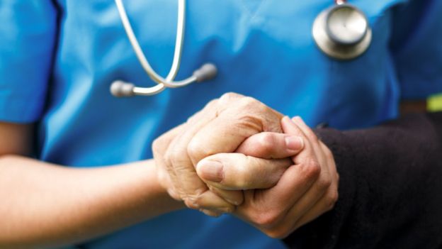 Nurse holding old man's hand