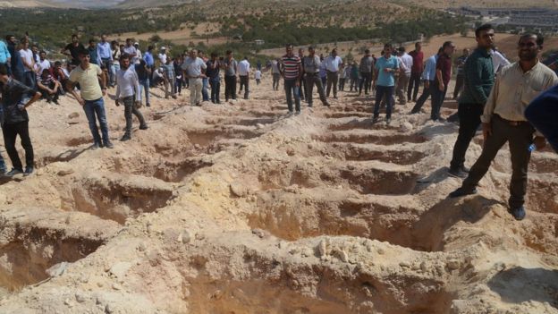 People wait close to empty graves at a cemetery during the funeral for the victims of last night's attack on a wedding party that left 50 dead in Gaziantep in south-eastern Turkey near the Syrian border on August 21, 2016.