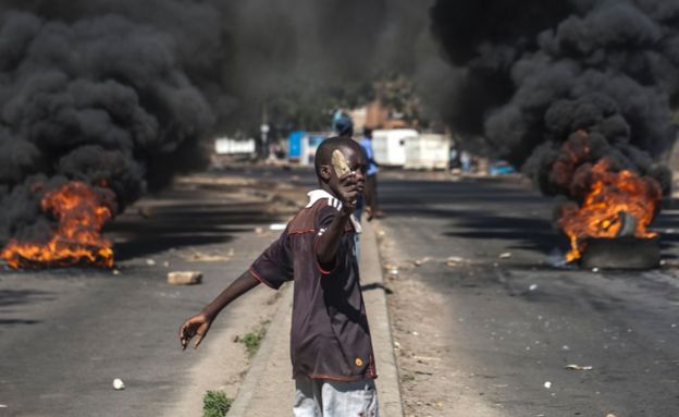 A protester throws rocks next to burning tyres during a demonstration on July 6 2016, in Bulawayo Zimbabwe