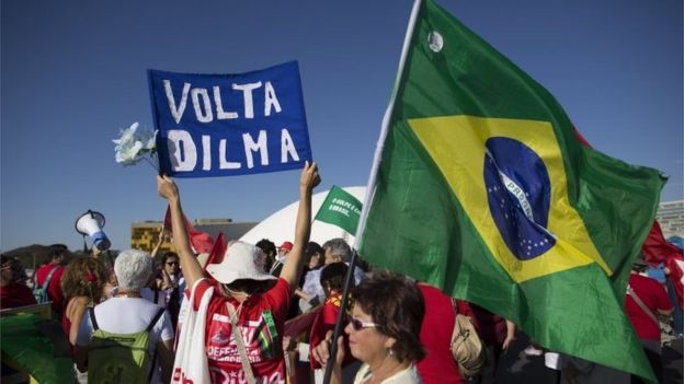 A demonstrator holds up a banner with a message that reads in Portuguese; 