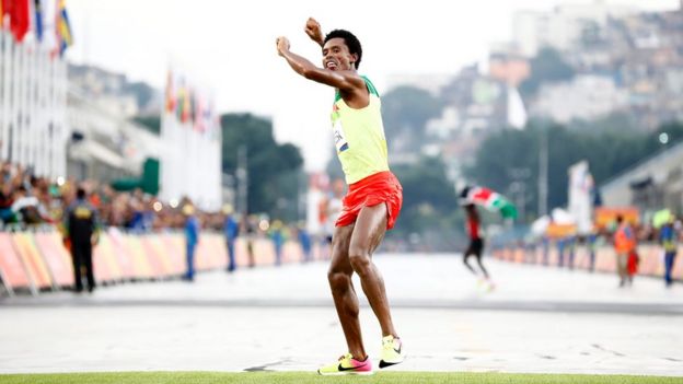 Feyisa Lilesa of Ethiopia celebrates while crossing the finish line to take the second place in the men
