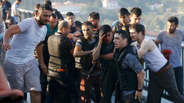 Policemen protect a soldier from a mob on the Bosphorus bridge in Istanbul on 16 July 2016