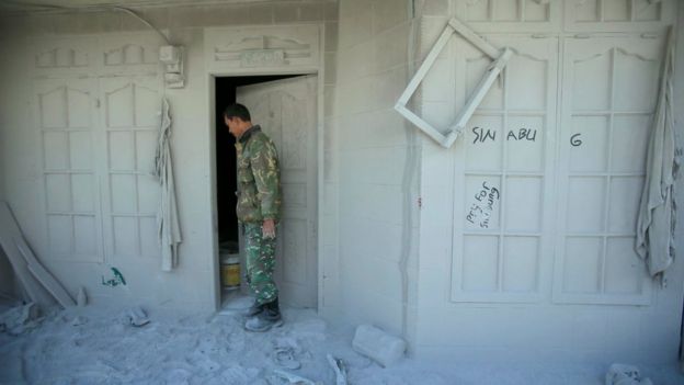 An Indonesian soldier inspects an abandoned house covered by volcanic ash on 23 May 2016