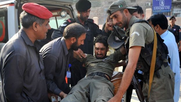 Pakistani security personnel help an injured comrade (C) to a hospital following an attack by militants on a Pakistan Air Force base in Peshawar on September 18, 2015.