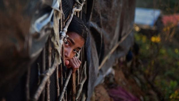 girl looking out from a makeshift shelter