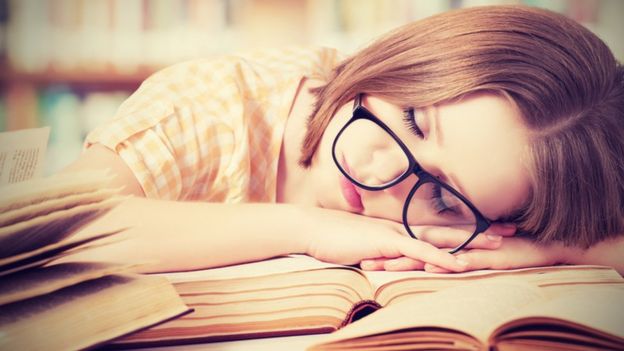 امرأة ناعسة أمام مجموعة من الكتب