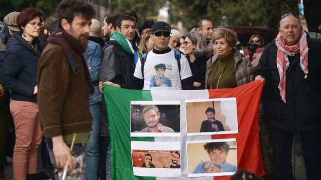 People hold an Italian flag with photos of Giulio Regeni during a demonstration in front of the Egypt's embassy in Rome on 25 February 2016