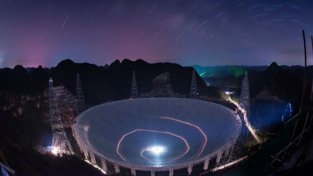 A vehicle leaves light trails in a long exposure photo as it drives beneath the Five-hundred-meter Aperture Spherical Telescope (FAST) in Pingtang County in southwestern China