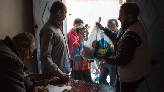 Syrian families receive aid packages in the rebel-held district of Marjah, Aleppo (15 November 2016)