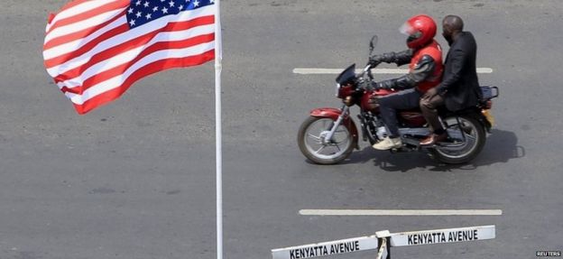 A motorcyclist rides past a US flag at a main street as the country prepares to receive U.S. President Barack Obama for his three-day state visit, in Kenya's capital Nairobi 24 July 2015