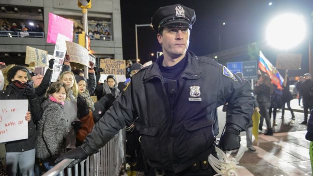Policial na barreira contra manifestantes no aeroporto JFK, em Nova York