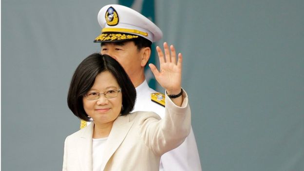 President Tsai Ing-wen waves to the crowd after her swearing in, with a man in a white military uniform standing behind her, in Taipei on 20 May 2016