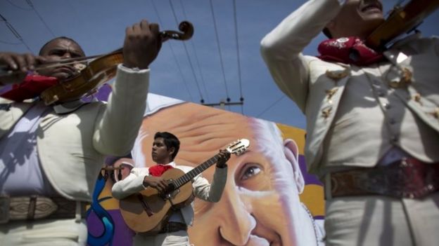 Mariachis play in front of street art depicting Pope Francis, as they wait for the Pope mobile to pass following the end of Mass, in Ecatepec (14 February 2016)