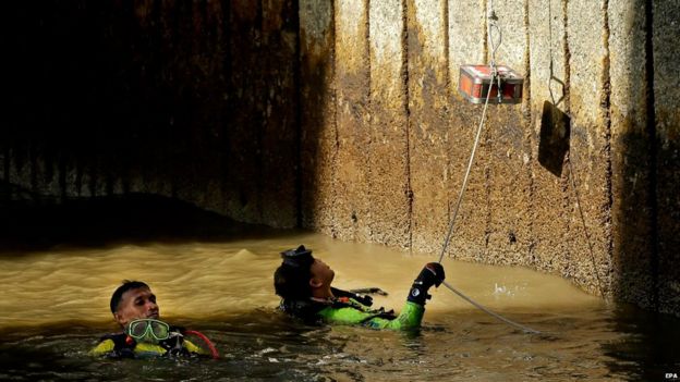 Divers retrieve and send up surviving pieces of an explosive device to be inspected at Sathorn pier, Bangkok, Thailand, on Tuesday after it was thrown towards the pier but exploded in the water without any casualties